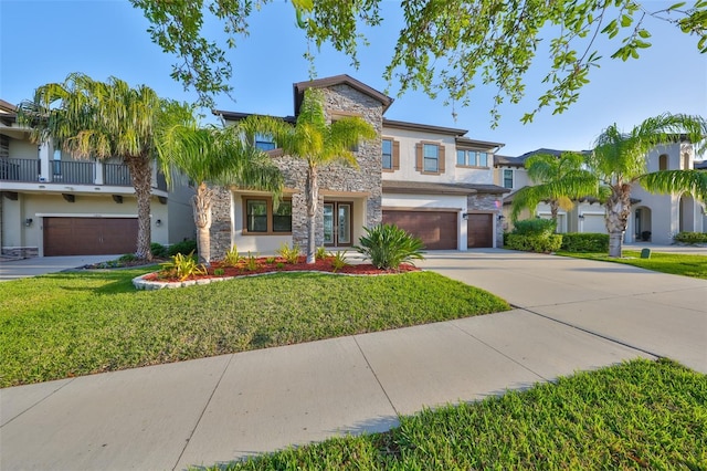 view of front of property featuring stone siding, a garage, concrete driveway, a front lawn, and stucco siding