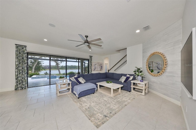 tiled living room with stairs, recessed lighting, a water view, visible vents, and ceiling fan