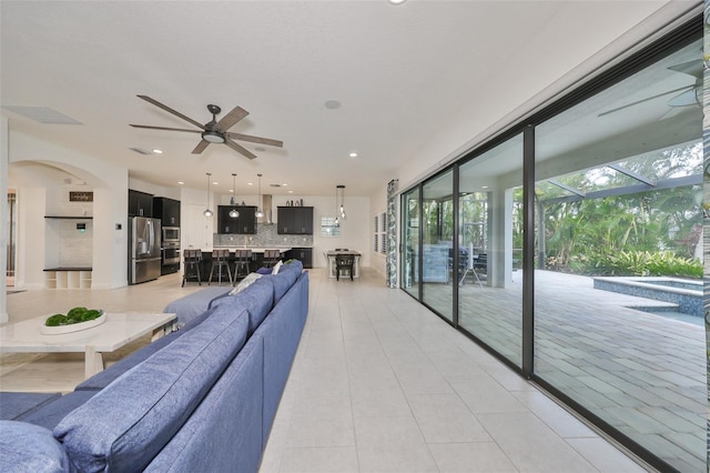 living area featuring light tile patterned flooring, arched walkways, recessed lighting, and ceiling fan