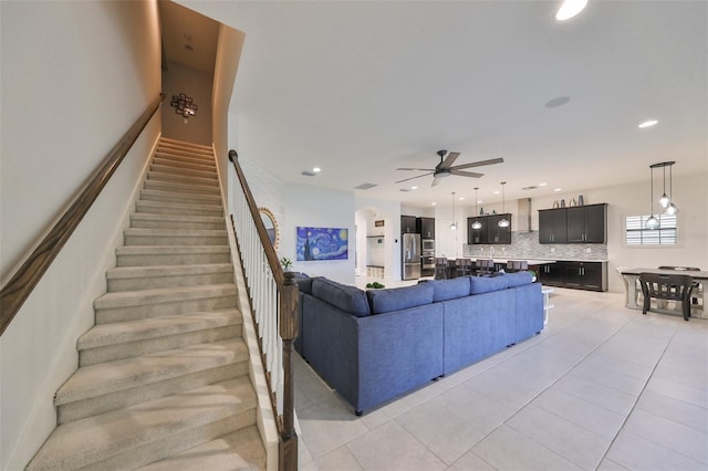 living room featuring stairs, recessed lighting, light tile patterned floors, arched walkways, and a ceiling fan