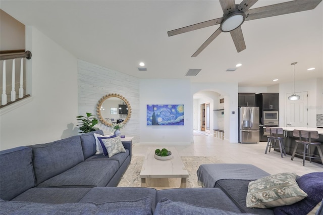 living area with arched walkways, ceiling fan, visible vents, and recessed lighting