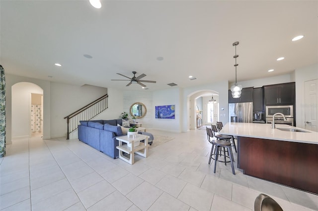 living room with arched walkways, recessed lighting, stairway, and a ceiling fan