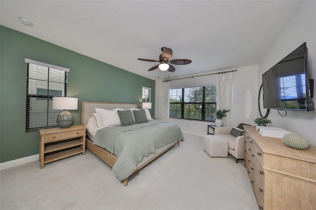 bedroom featuring a ceiling fan, light carpet, and baseboards