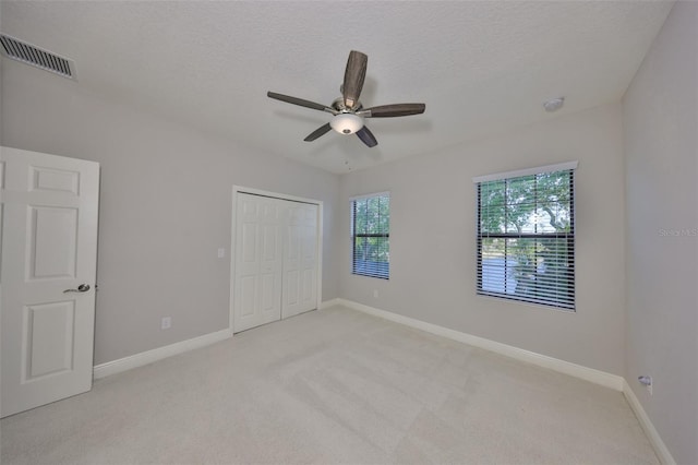 unfurnished bedroom with light carpet, baseboards, visible vents, and a textured ceiling
