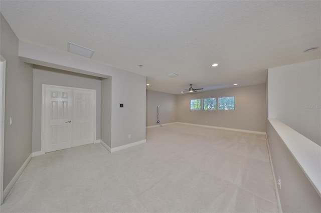 below grade area featuring light carpet, baseboards, and ceiling fan