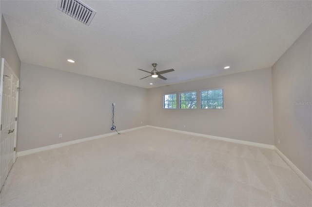 unfurnished room with baseboards, a textured ceiling, visible vents, a ceiling fan, and light carpet