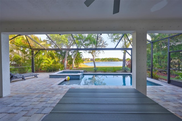 view of pool featuring glass enclosure, a water view, a patio, and a pool with connected hot tub