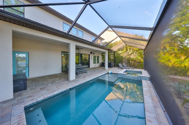 view of pool with glass enclosure, ceiling fan, a pool with connected hot tub, and a patio area