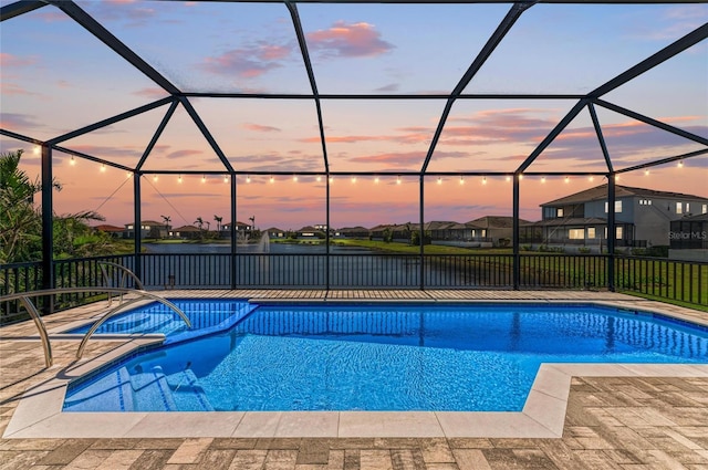 pool at dusk with a lanai, a pool with connected hot tub, a residential view, and a patio