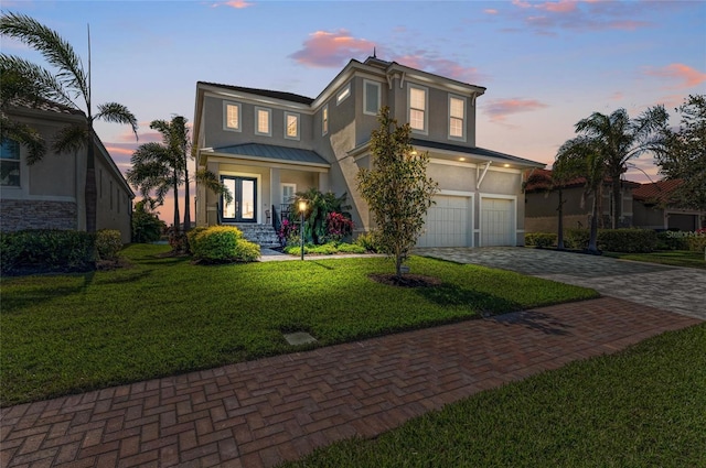 view of front of property with metal roof, french doors, decorative driveway, stucco siding, and a front lawn