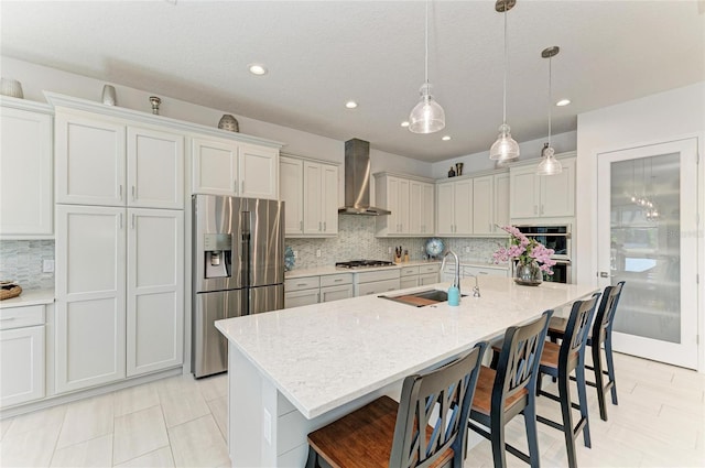 kitchen with wall chimney exhaust hood, a breakfast bar area, appliances with stainless steel finishes, and a sink