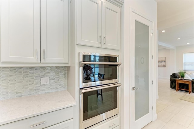 kitchen featuring light tile patterned floors, tasteful backsplash, recessed lighting, double oven, and light stone countertops