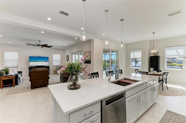 kitchen featuring hanging light fixtures, stainless steel dishwasher, a sink, and visible vents