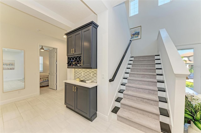 stairs with a ceiling fan, a healthy amount of sunlight, and baseboards