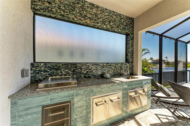 view of patio / terrace with a lanai, a sink, and an outdoor kitchen