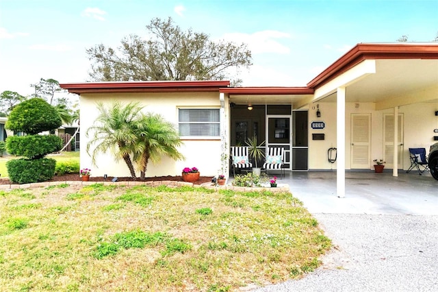 view of front of property with a carport, a front yard, driveway, and stucco siding