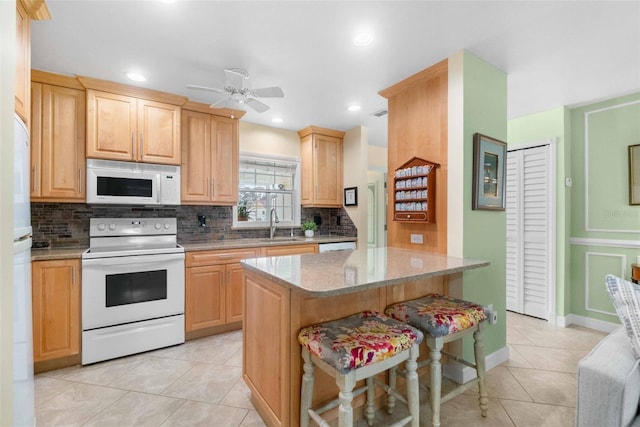 kitchen featuring light tile patterned floors, white appliances, a sink, backsplash, and light brown cabinetry