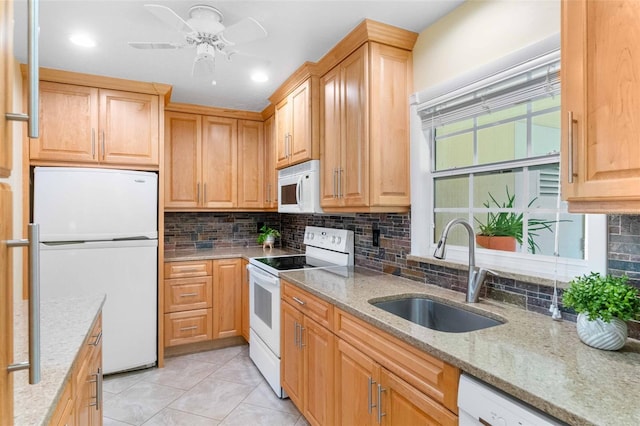 kitchen featuring white appliances, a sink, light stone counters, and tasteful backsplash