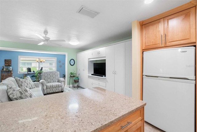 kitchen featuring visible vents, open floor plan, ceiling fan with notable chandelier, and freestanding refrigerator