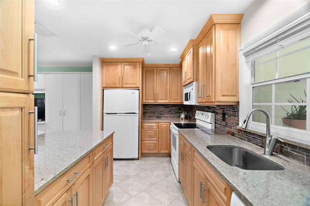 kitchen featuring white appliances, decorative backsplash, ceiling fan, light stone counters, and a sink