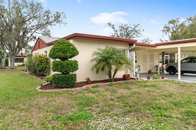 view of side of property with an attached carport, a yard, and stucco siding