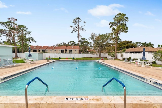 community pool featuring a residential view, fence, and a patio