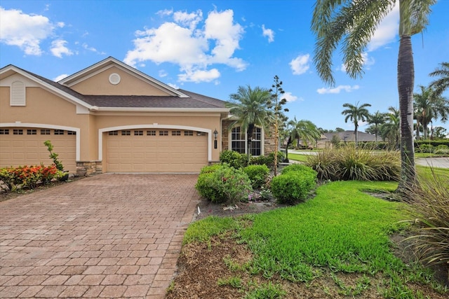 view of front of property with a garage, stone siding, decorative driveway, and stucco siding