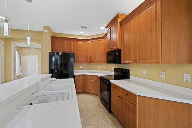 kitchen with light countertops, hanging light fixtures, brown cabinetry, a sink, and black appliances