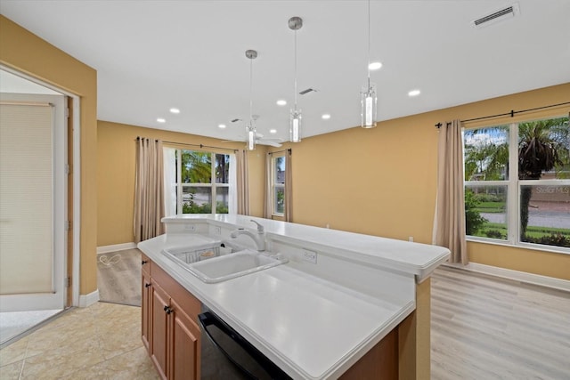 kitchen with a healthy amount of sunlight, dishwasher, a kitchen island with sink, and a sink