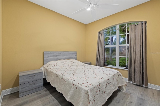 bedroom with multiple windows, wood finished floors, a ceiling fan, and baseboards