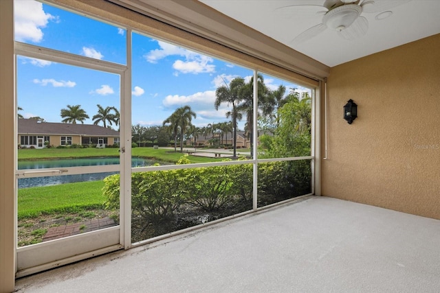 unfurnished sunroom featuring a water view and ceiling fan