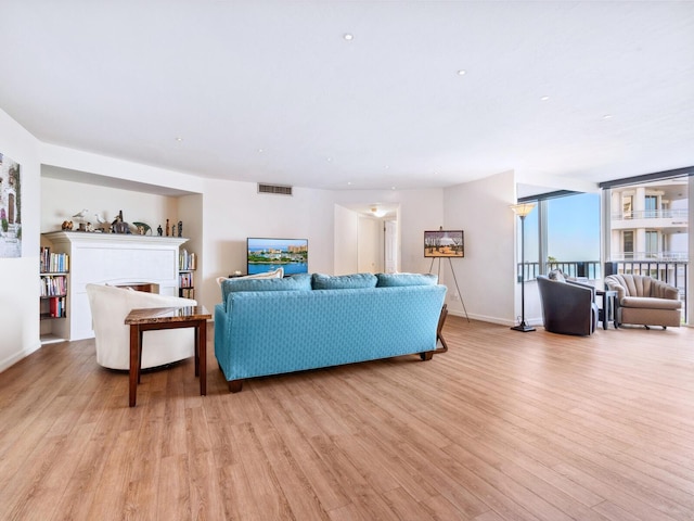 living room with baseboards, visible vents, a fireplace, and light wood finished floors