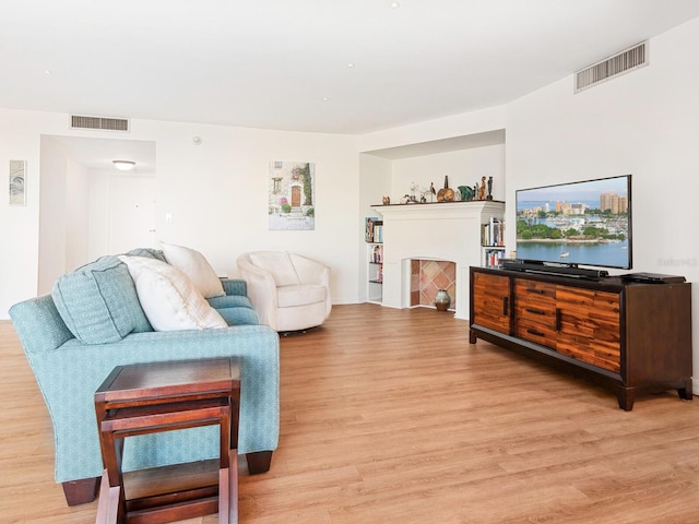 living area with visible vents, a fireplace, and light wood finished floors