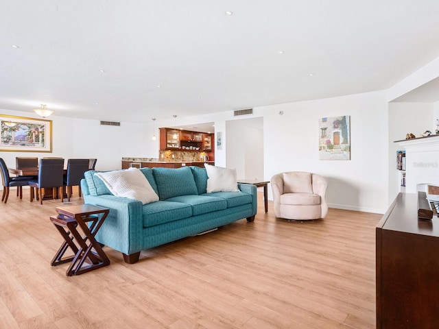 living room with light wood-type flooring, baseboards, and visible vents