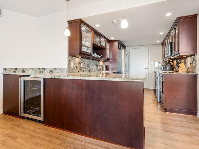 kitchen with beverage cooler, tasteful backsplash, glass insert cabinets, appliances with stainless steel finishes, and light wood-style floors