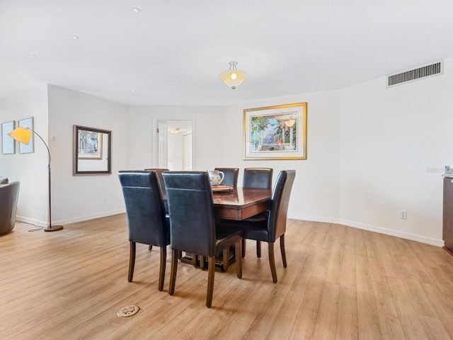 dining space with light wood finished floors, visible vents, and baseboards