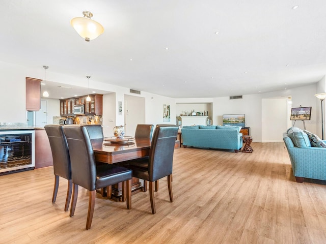 dining room with light wood-style flooring, visible vents, and beverage cooler