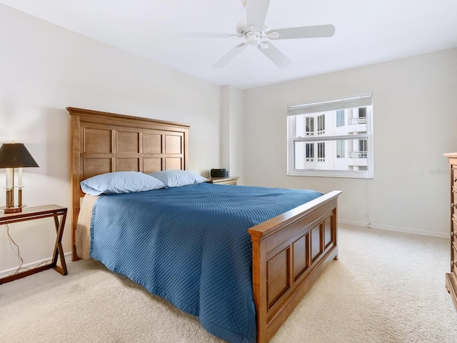 bedroom with a ceiling fan, light carpet, and baseboards