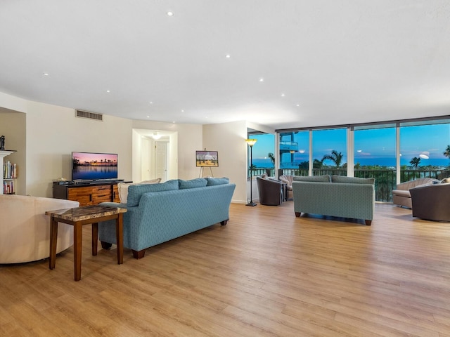 living area with floor to ceiling windows, recessed lighting, visible vents, and light wood-style floors