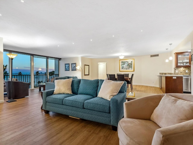 living area with light wood-type flooring, baseboards, visible vents, and expansive windows