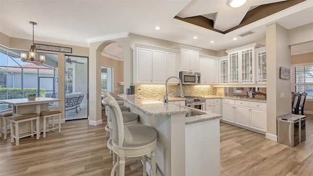 6621 The Masters Ave, Lakewood Ranch, FL 34202 - kitchen featuring stainless steel appliances, crown molding, a kitchen breakfast bar, a peninsula, and white cabinets