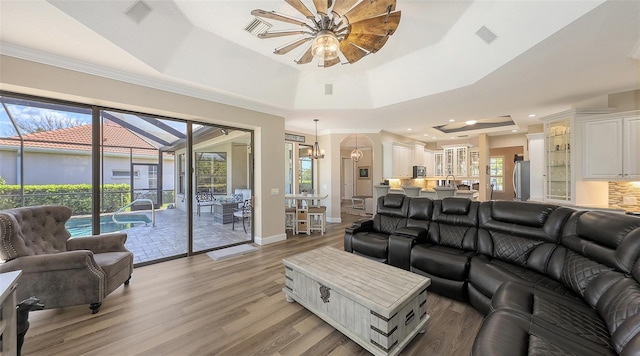 6621 The Masters Ave, Lakewood Ranch, FL 34202 - living area featuring a tray ceiling, a ceiling fan, light wood-type flooring, a chandelier, and baseboards