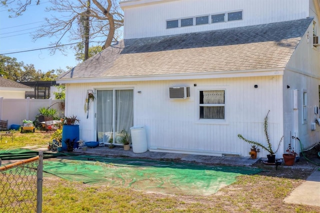 2564 Wood St, Sarasota, FL 34237 - back of property featuring a shingled roof, fence, and an AC wall unit