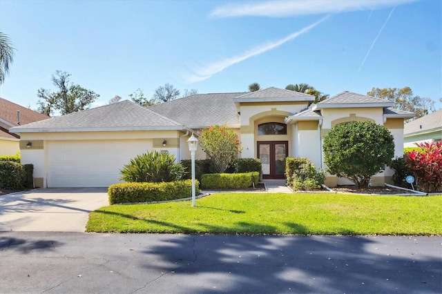 view of front facade featuring an attached garage, driveway, french doors, stucco siding, and a front yard