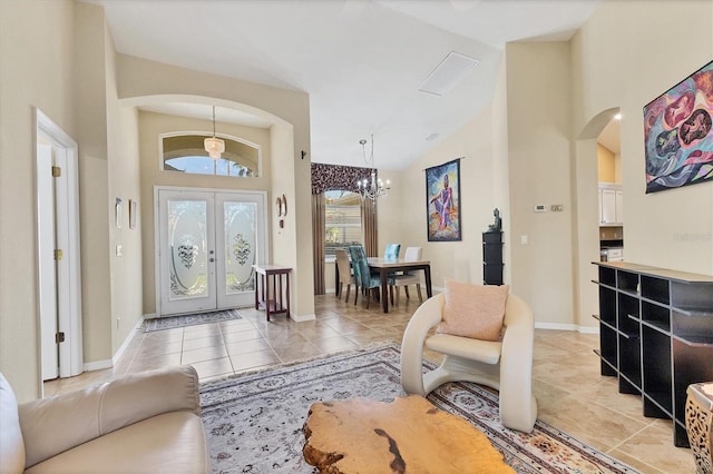 foyer entrance featuring arched walkways, french doors, light tile patterned floors, high vaulted ceiling, and baseboards