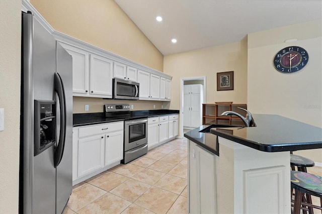 kitchen featuring light tile patterned floors, appliances with stainless steel finishes, dark countertops, and a sink