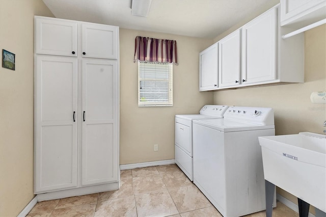 clothes washing area with cabinet space, a sink, baseboards, and separate washer and dryer