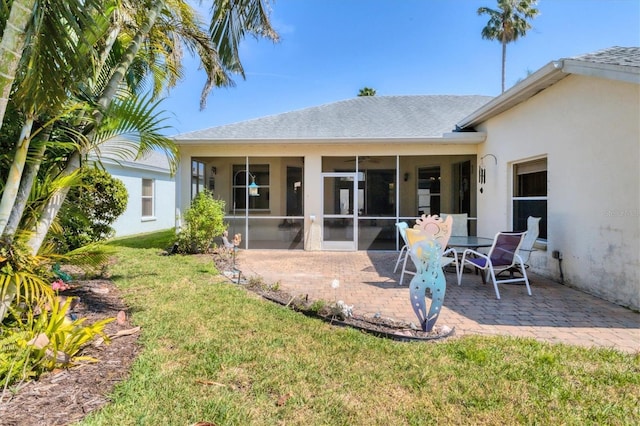 back of house featuring a sunroom, stucco siding, a lawn, and a patio