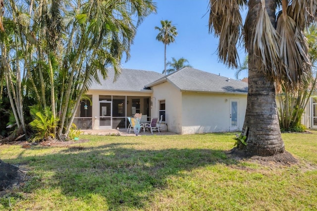 rear view of house featuring a sunroom, a lawn, a patio, and stucco siding