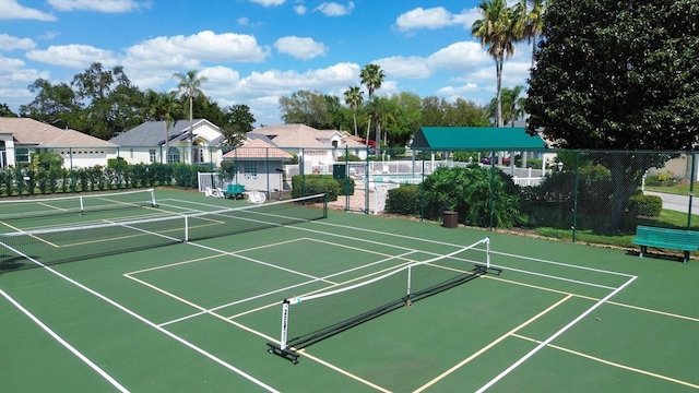 view of tennis court featuring a residential view and fence